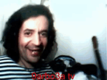 a man in a striped shirt is smiling in a blurry photo with the words garboza tv in red .