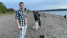 a man in a plaid shirt stands next to a woman on the beach