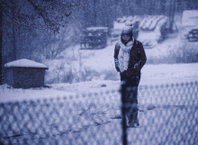 a person wearing a scarf and a hat is walking in the snow