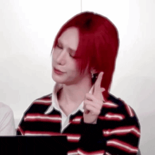 a young man with red hair is sitting in front of a laptop computer .