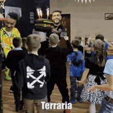 a group of children are dancing in front of a man holding a cake with the word terraria written on the bottom