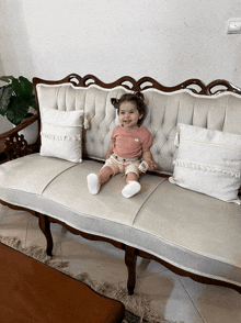 a little girl sitting on a couch with white pillows