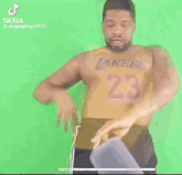 a man wearing a lakers jersey is dancing on a green screen .