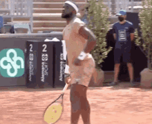 a man is holding a tennis racquet in front of a sign that says ' alemania sport ' on it