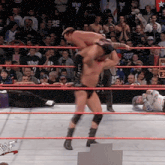 a man in a wrestling ring is carrying another man on his shoulders while a crowd watches
