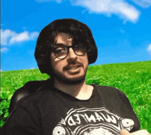 a man wearing glasses and a t-shirt that says city jaw is sitting in a chair in front of a grassy field