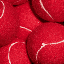 a pile of red tennis balls with white stitching