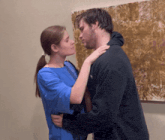 a man and a woman are kissing in front of a painting on the wall
