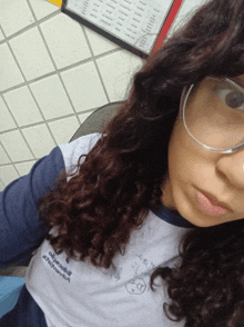 a girl with curly hair wearing glasses and a shirt that says " a.m.v. "