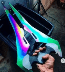 a person is holding a rainbow painted sword in their hand .