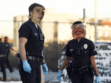 two police officers are standing next to each other with one wearing a mask and the other wearing glasses