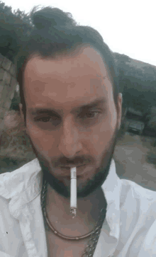 a man with a beard is smoking a cigarette and wearing a white shirt