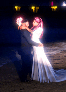 a bride and groom pose for a picture on the beach