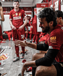 a man in a red shirt that says western union sits in a locker room