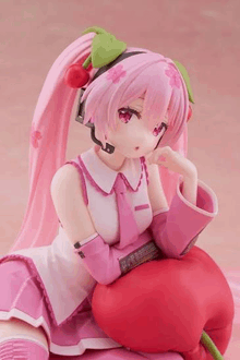 a statue of hatsune miku sitting on a cherry .