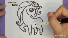 a person is drawing a unicorn with a marker on a piece of paper that says draw cute things