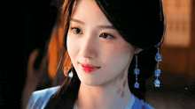 a close up of a woman 's face wearing a blue dress and earrings