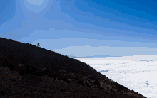 a silhouette of a person riding a bike on top of a mountain above the clouds