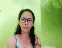 a woman wearing glasses and a blue bra is looking at the camera .