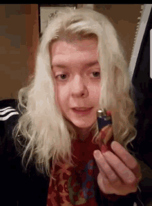 a woman with long blonde hair is holding a lighter in her hand