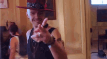 a man wearing a red hat and a black tank top is giving a peace sign