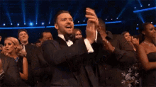 a man in a tuxedo is applauding while sitting in a crowd of people at an event sponsored by abc