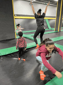 a woman jumping on a trampoline with a girl wearing a red shirt that says ' aa '