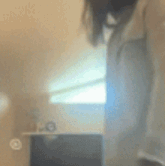 a blurry picture of a person standing in front of a window with a watermark on the bottom left