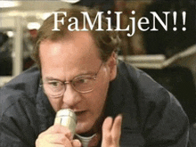 a man wearing glasses is talking into a microphone with the words " familien " behind him