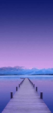 a dock with mountains in the background and a purple sky