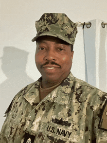 a man in a u.s. navy uniform stands in front of a white curtain