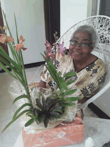 an elderly woman sits in a chair with a box of flowers