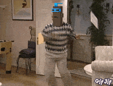 a man in a striped sweater is dancing in a living room with gif jif written on the bottom right