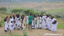 a group of people are standing in a field with a man in a green shirt standing in the middle .