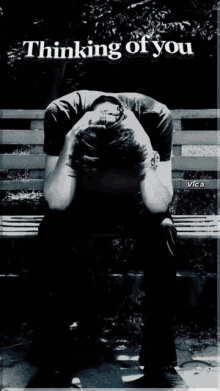 a black and white photo of a man sitting on a bench with the words thinking of you above him