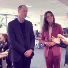 a man in a suit and a woman in a pink suit are standing next to each other in an office