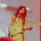 a woman is singing into a microphone while playing a guitar