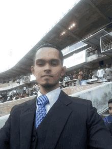 a man in a suit and tie is taking a selfie in front of a stadium