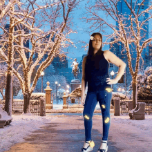 a woman stands in front of a snowy park with a statue of a man on a horse in the background