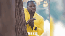 a man in a yellow suit is peeking out from behind a tree and says yessss