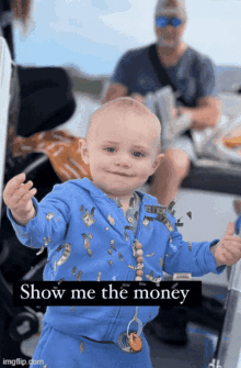 a baby wearing a blue outfit with money on it and the words show me the money