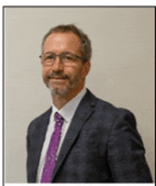 a man in a suit and purple tie is smiling