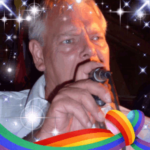 a man singing into a microphone in front of a rainbow