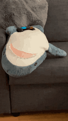 a stuffed shark laying on a couch with a nintendo switch on its head