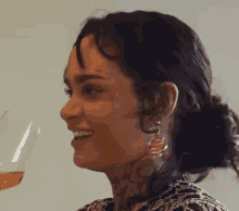 a woman with a tattoo on her face is holding a glass of wine and smiling .