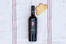 a bottle of wine sits on a table next to a heart shaped cookie