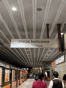 a sign that says stacja koniecowa terminus hangs from the ceiling