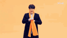 a man in a suit is holding an orange scarf around his neck in front of an x tvn logo