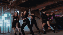 a group of women are dancing in a dark room in front of a car