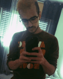 a man wearing glasses takes a selfie with his cell phone